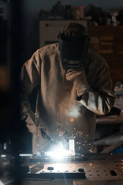 Фронтальный вид сварщика в защитной маске, работающей с металлом на заводе — стоковое фото