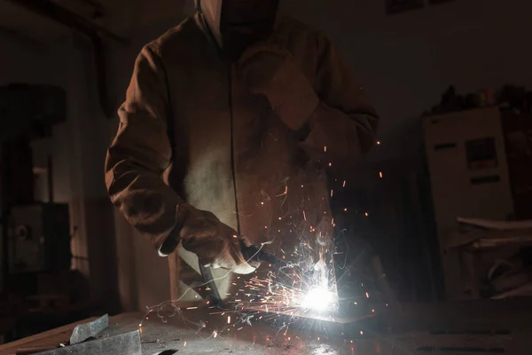 Abgeschnittenes Bild eines Arbeiters mit Schutzmaske beim Schweißen von Metall in der Fabrik — Stockfoto