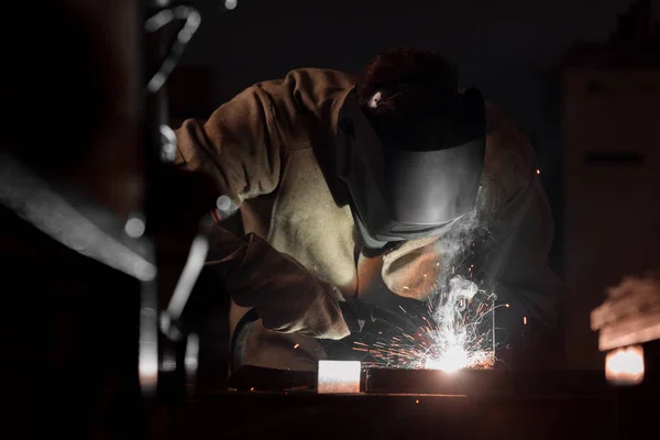 Vue de face du soudeur dans le masque de protection travaillant avec du métal à l'usine — Photo de stock