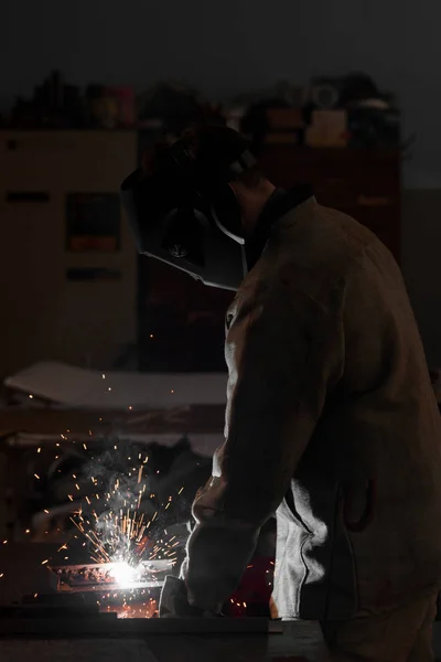 Vue latérale du travailleur de la fabrication soudant le métal avec des étincelles à l'usine — Photo de stock