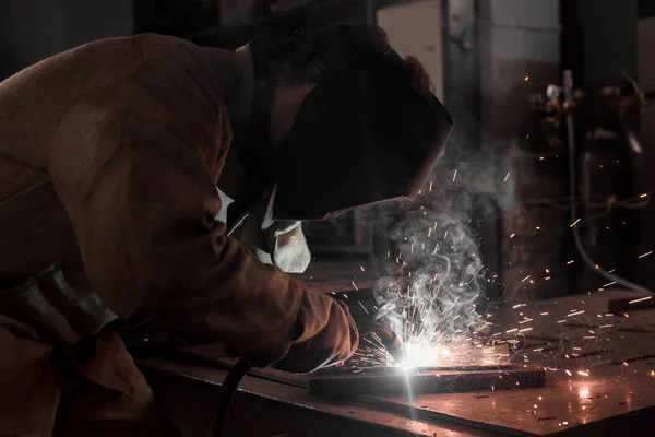 Вид збоку працівника в захисній масці зварювання металу на заводі — стокове фото
