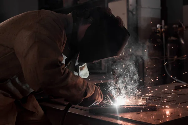 Vista laterale del lavoratore nella maschera di protezione saldatura metallo in fabbrica — Foto stock