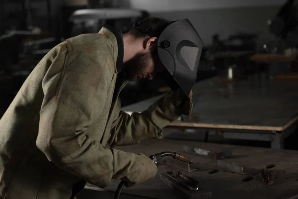 Welder lifting up protective mask to look at his work at factory — Stock Photo