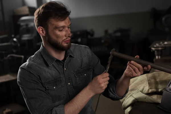 Young male worker measuring metal part at factory — Stock Photo