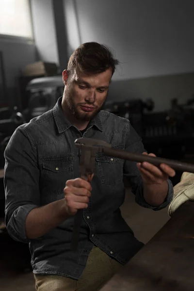 Young workman measuring metal part at factory — Stock Photo