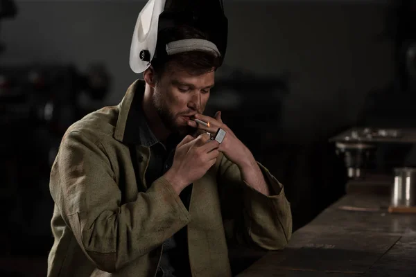 Чоловік працівник з піднятою захисною маскою блискавка сигарета на заводі — стокове фото