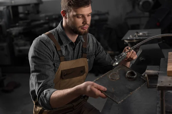 Arbeiter schaut mit Lupe auf Metallteil — Stockfoto