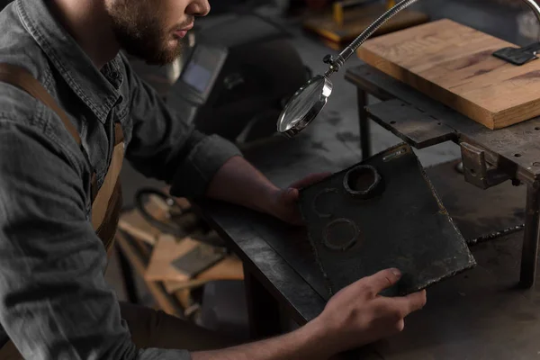 Cropped shot of workman looking with magnifying glass looking at metal part — Stock Photo