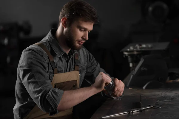 Young male worker opening bottle of water and sitting at table — Stock Photo