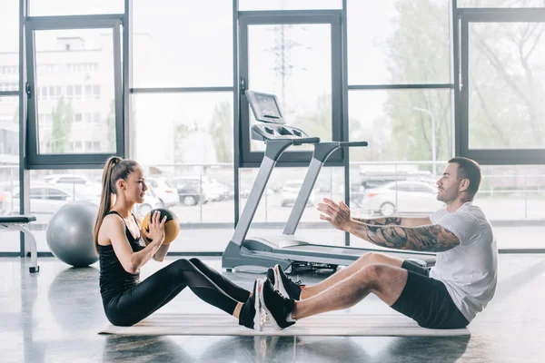 Entrenador personal masculino y deportista haciendo ejercicios con pelota en el gimnasio — Stock Photo
