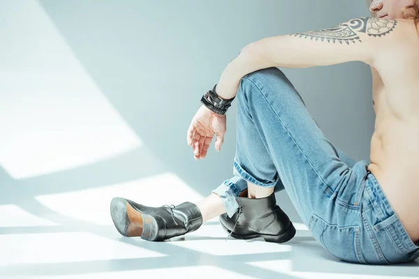 Cropped view of sexy man sitting in jeans, on grey — Stock Photo