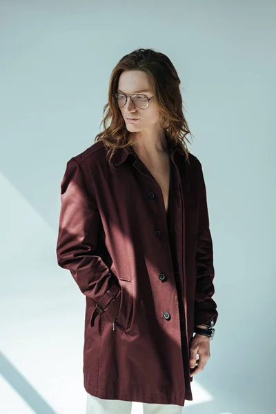 Homem elegante com cabelos longos posando em casaco de trincheira, em cinza — Fotografia de Stock