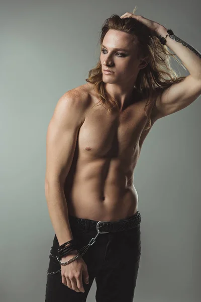 Shirtless sexy man with long hair posing in black jeans, on grey — Stock Photo