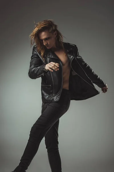 Shirtless man posing in black jeans and leather jacket, isolated on grey — Stock Photo