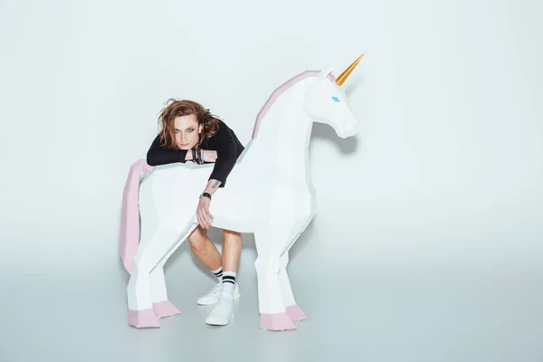 Homme élégant posant en veste noire avec grande licorne blanche, sur gris — Photo de stock