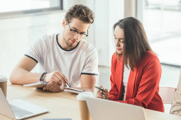 Diverse business team working on project by the table with laptops in light workspace — Stock Photo