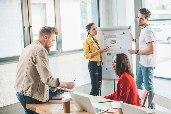 Diverse business team working on project by whiteboard in light workspace — Stock Photo