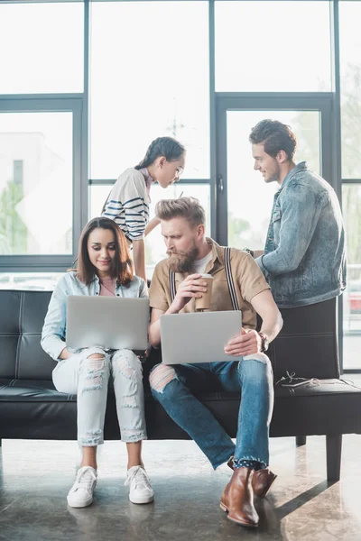 Successful business people working on laptops and discussing project in modern light office — Stock Photo