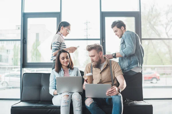 Diversifiziertes Business-Team arbeitet an Laptops und diskutiert Projekt in hellem Arbeitsbereich — Stockfoto