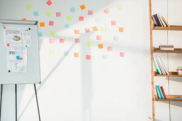 Доска с графиками и белая доска с липкими нотами в современном светлом офисе — стоковое фото