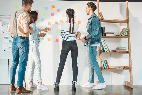 Professional business colleagues men and women looking at white board with sticky notes in modern office — Stock Photo