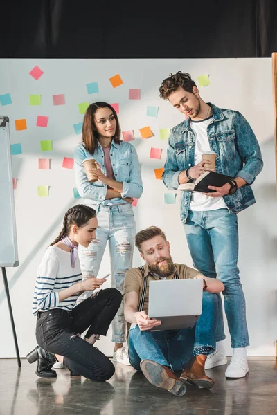 Uomini d'affari di successo guardando il loro collega di sesso maschile che lavora sul computer portatile in ufficio luce moderna — Foto stock