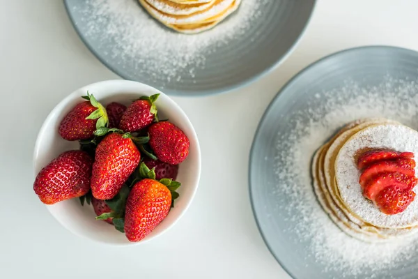 Top view of pancakes with ripe strawberries on table at kitchen — Stock Photo