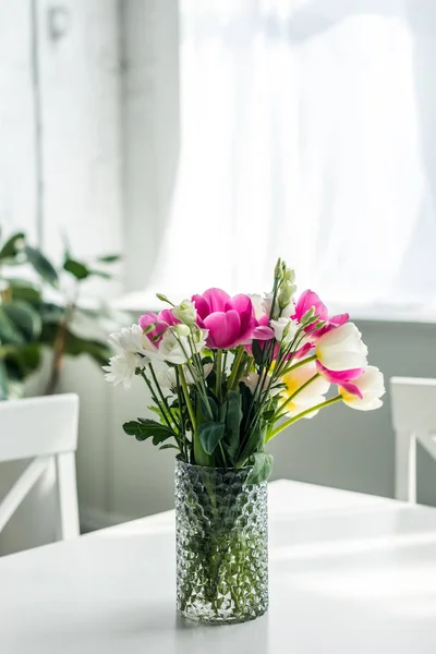 Bouquet of beautiful colored flowers on white tabletop at kitchen — Stock Photo