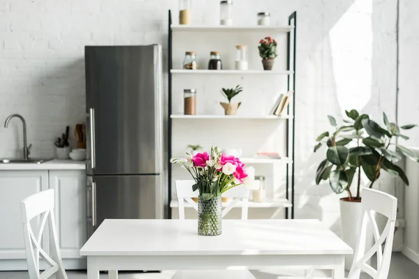 Interior da cozinha moderna luz com buquê de tulipas na mesa — Fotografia de Stock