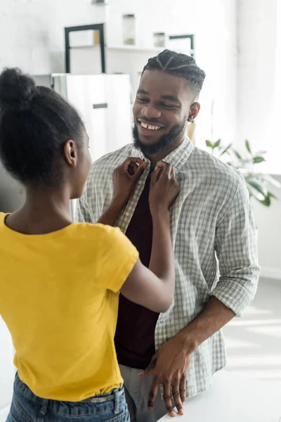 Africana americana novia buttoning novios camisa en cocina - foto de stock