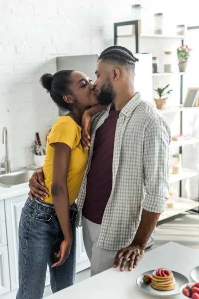 Africano americano pareja besos en cocina - foto de stock
