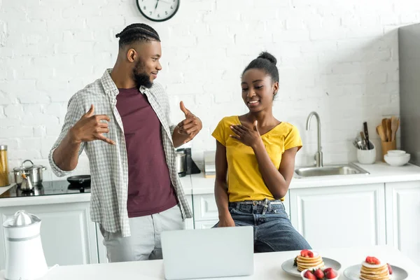 African american couple gesturing while using laptop at kitchen — Stock Photo