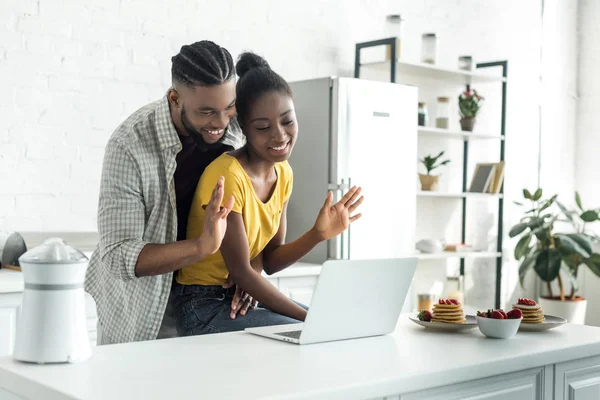 Couple afro-américain agitant les mains lors d'un appel vidéo à la cuisine — Photo de stock