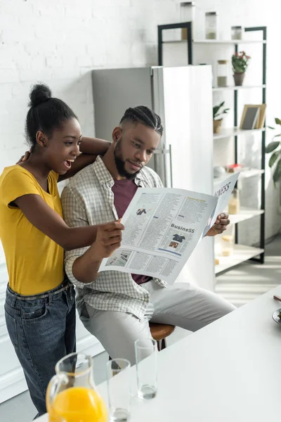 Coppia afro-americana leggendo giornale in cucina — Foto stock