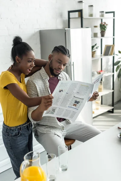 Pareja afroamericana leyendo periódico en cocina - foto de stock