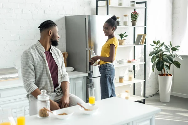 Africano casal americano olhando uns para os outros durante o café da manhã na cozinha — Fotografia de Stock