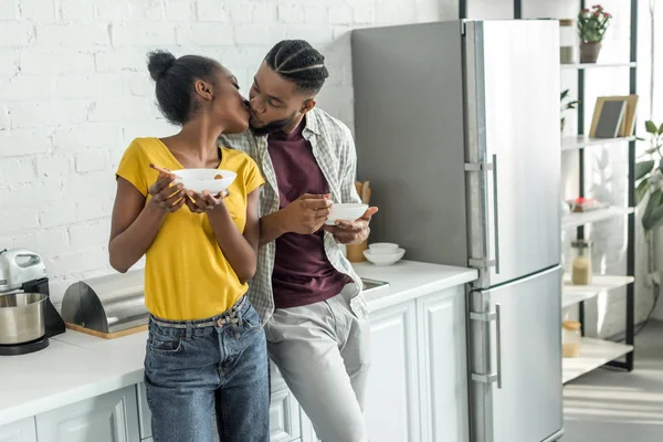 African american couple kissing while having breakfast at kitchen — Stock Photo