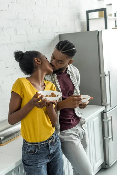 African american couple kissing while having breakfast at kitchen — Stock Photo