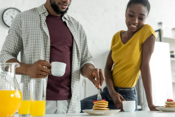 Cropped image of african american boyfriend taking pancakes at kitchen — Stock Photo