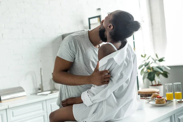 African american boyfriend kissing girlfriend neck at kitchen — Stock Photo