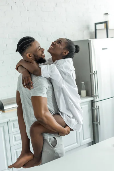 Afro-americano namorado segurando namorada na cozinha — Fotografia de Stock