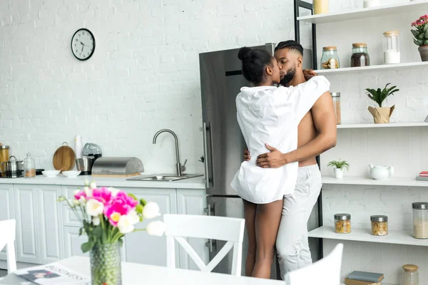 Sensual african american couple standing and kissing at kitchen — Stock Photo