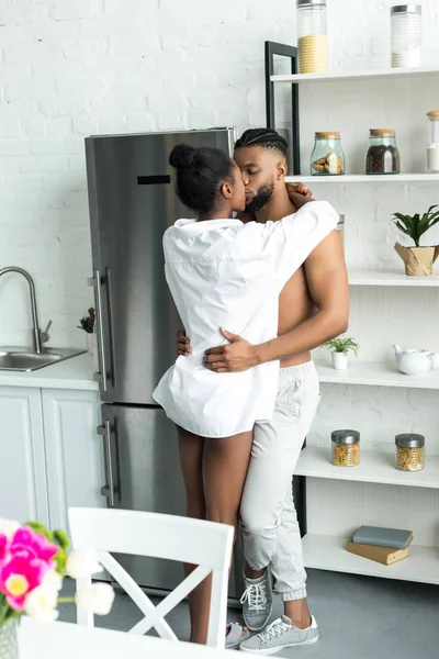 Романтическая африканская американская пара стоящая и целующаяся на кухне — стоковое фото