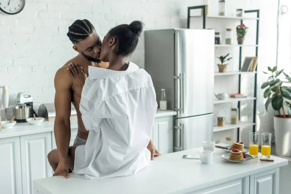 Seductive african american couple kissing on kitchen counter at kitchen — Stock Photo