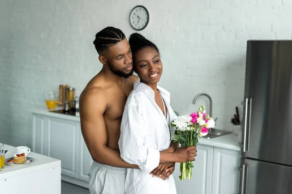 Afrikanisch-amerikanischer freund umarmt freundin und sie schauen weg von küche — Stockfoto