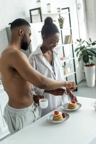Africano casal americano comer panquecas na cozinha — Fotografia de Stock