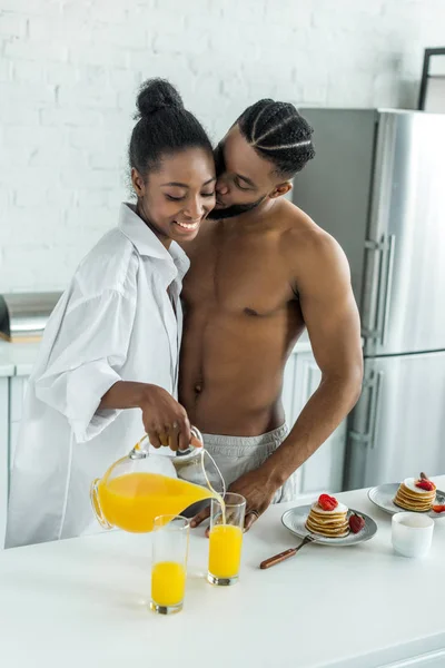 Africano americano novio besos novia en cocina - foto de stock