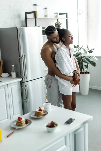 Africano americano pareja abrazos en cocina - foto de stock