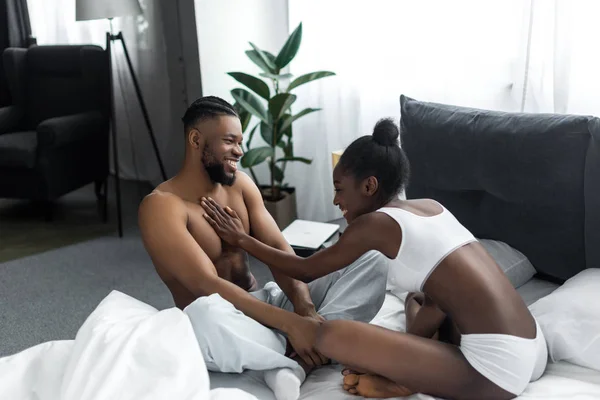 Africano americano novia tocando novio pecho en dormitorio - foto de stock