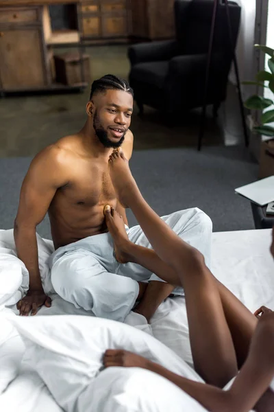 Image recadrée de couple afro-américain assis sur le lit dans la chambre — Photo de stock